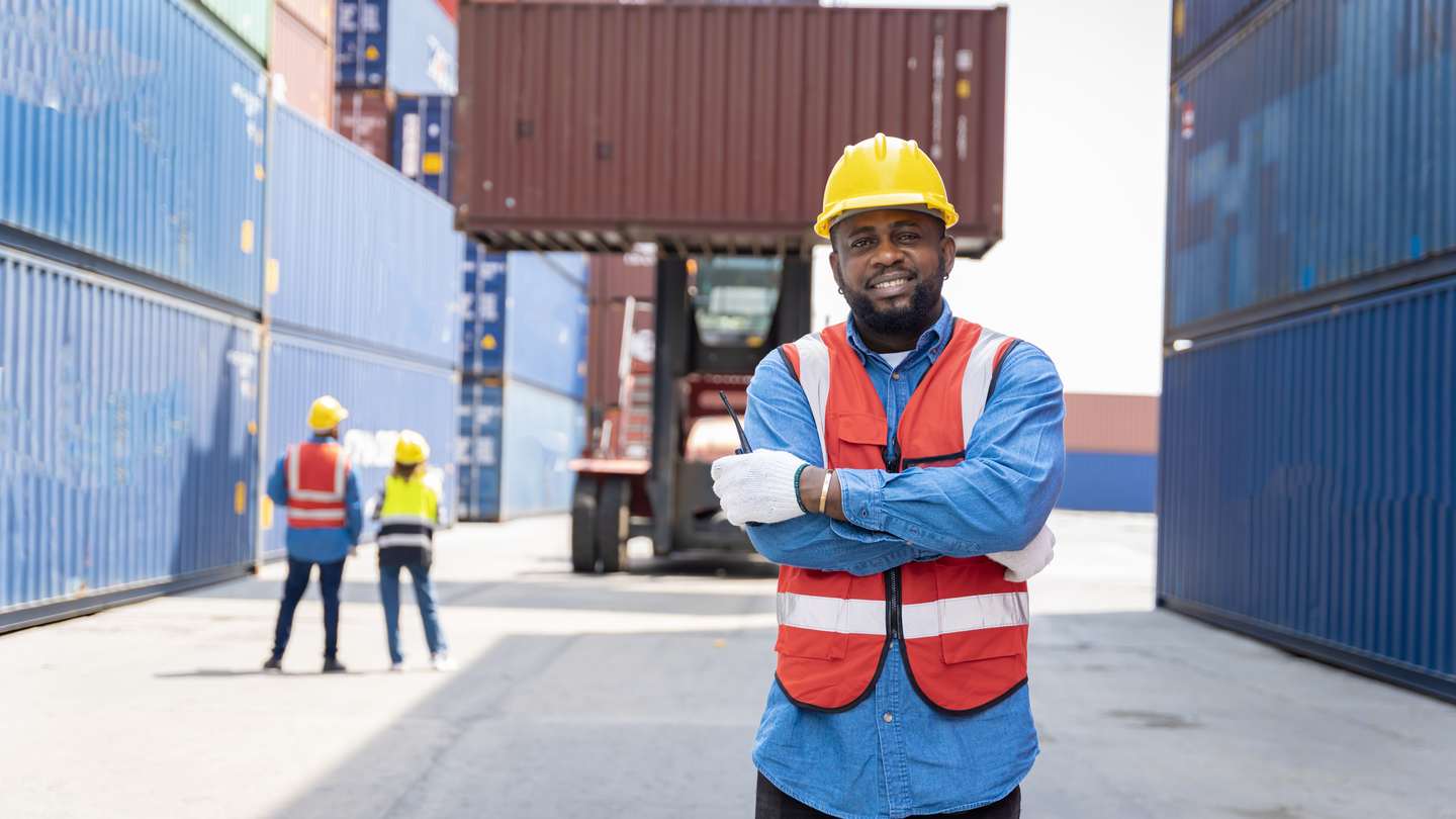 Logistics worker standing between shipping containers